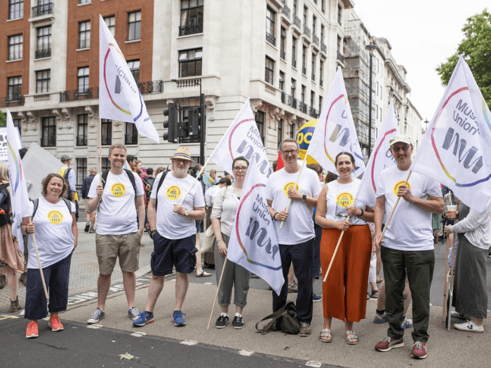 A group of Musicians' Union members and staff holding flags and wearing matching t-shirts.