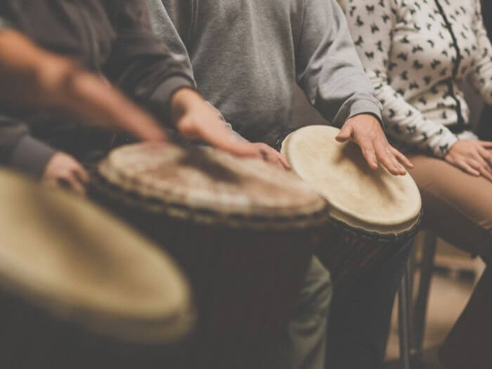 Close up of group of people playing drums, therapy by music concept.