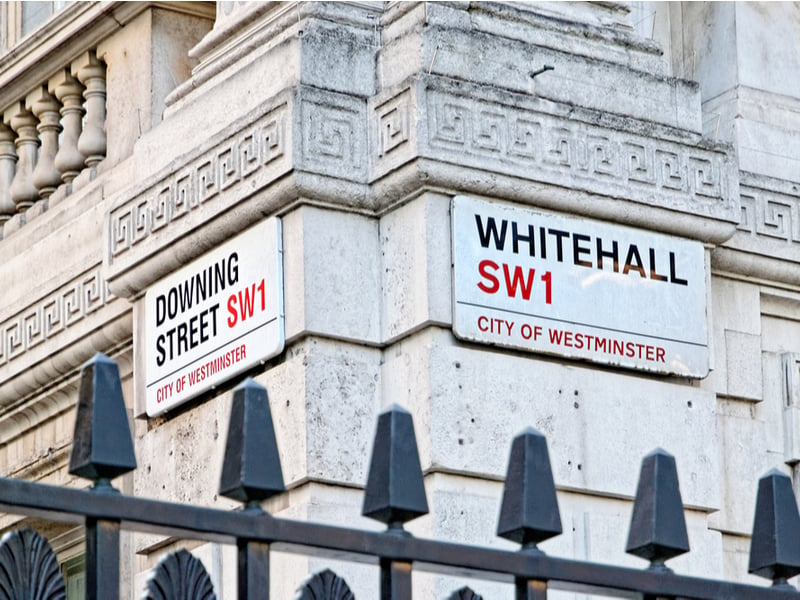 Photograph of the corner between Downing Street and Whitehall, focusing on the two street signs.