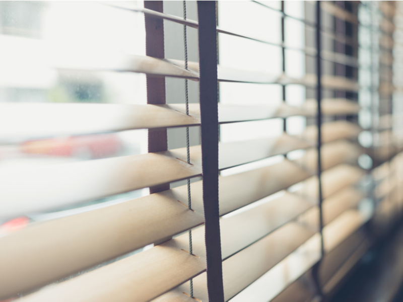 Photograph of semi closed blinds covering a window.