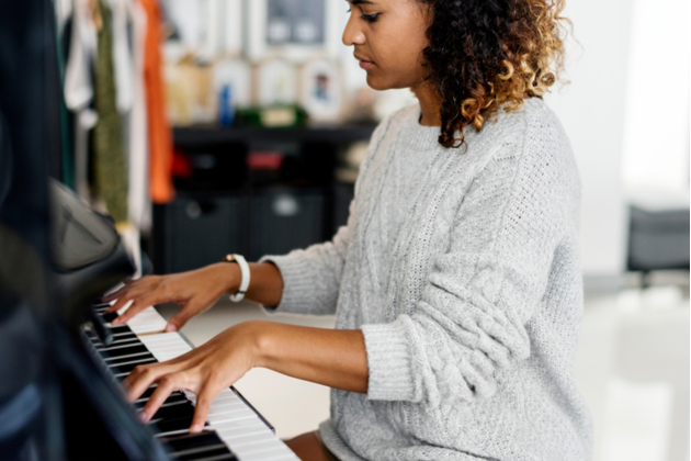 Photograph of a young woman, concentrating on playing the piano.