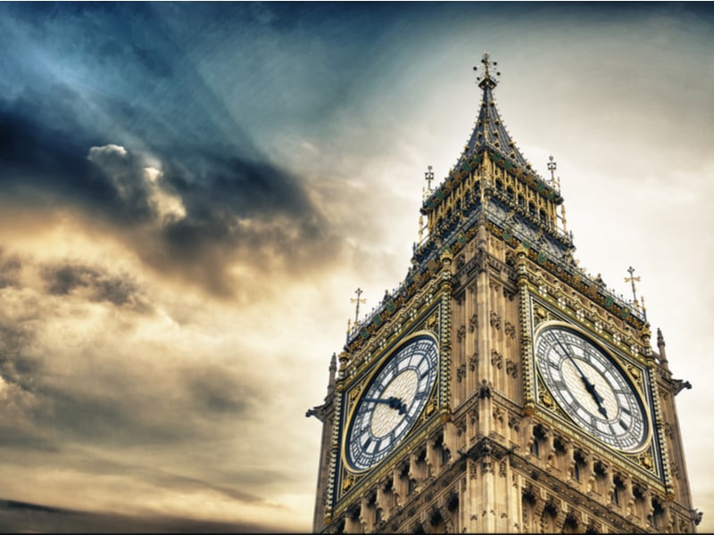 Photograph of the clock face of Big Ben against a stormy looking pink and grey sky.