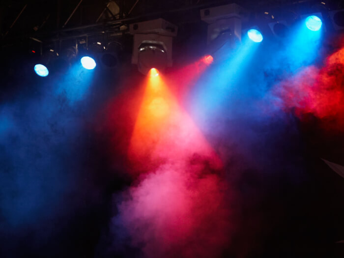 Bright and colourful stage lights beam through the smoke.