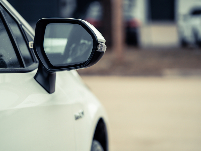 Photograph of a white car from the side, zoomed in on the wing mirror.