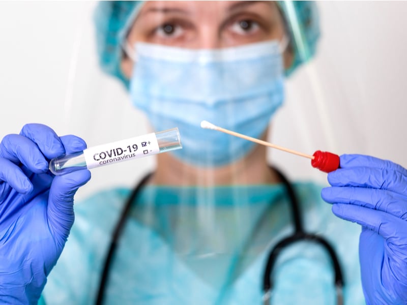Photograph of a nurse holding out a covid testing kit.