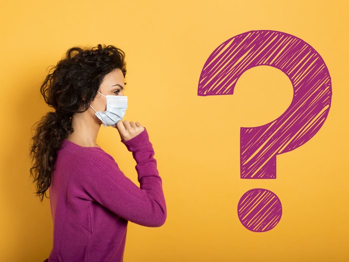 a woman in a surgical mask facing a question mark