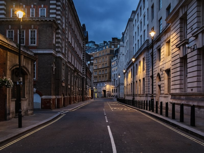 Photograph of a well lit London street at night, standing empty.
