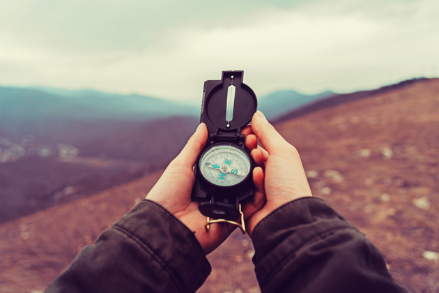 Hiker searching direction with a compass in the mountains. Point of view shot
