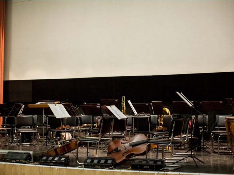 Photograph of an empty orchestral seating area, with some instruments left behind.