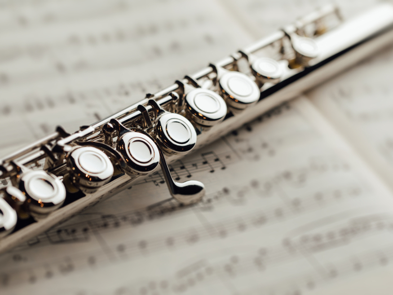 A flute left lying flat across a piece of blurred out sheet music.