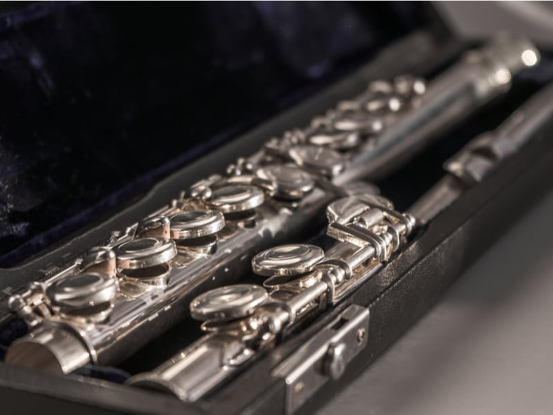 Photograph of a silver flute in a dark coloured case.