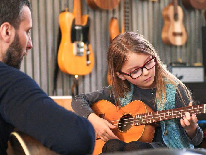 School age kid learning guitar with private teacher