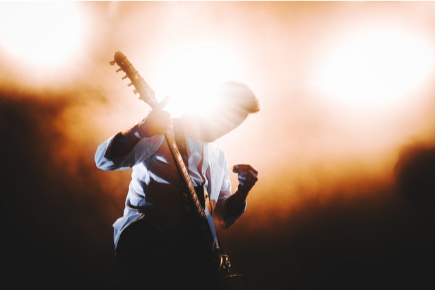 musician with a guitar on the stage with the backlight