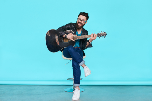 Happy man with a guitar against blue background