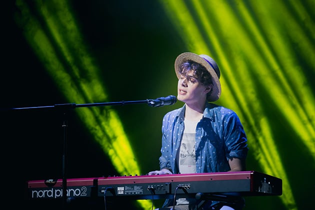 Photograph of Henry singing and playing a nord piano keyboard at the Pride In London contest