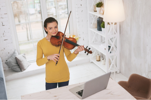 A woman learning to play violin at home remotely