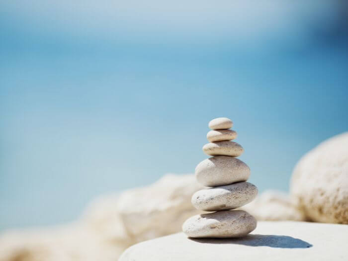 stacked rocks on the shore against blue sky