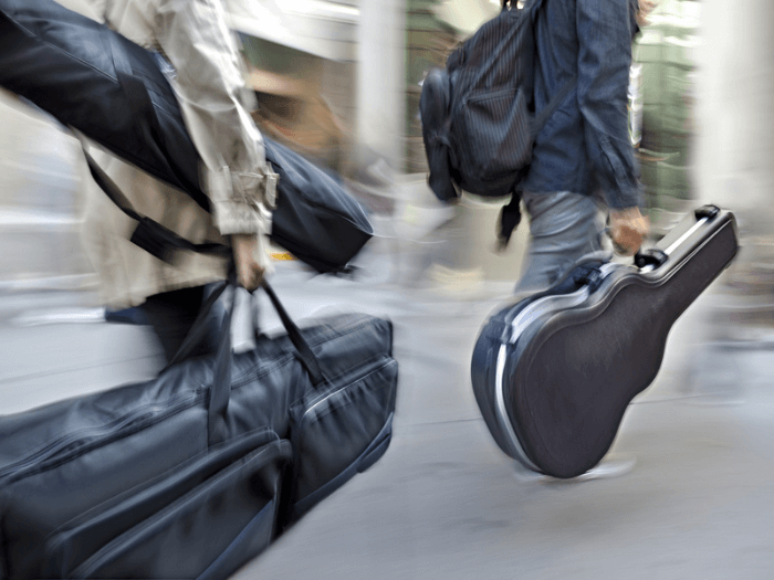 Two musicians walking with instrument cases down the street.