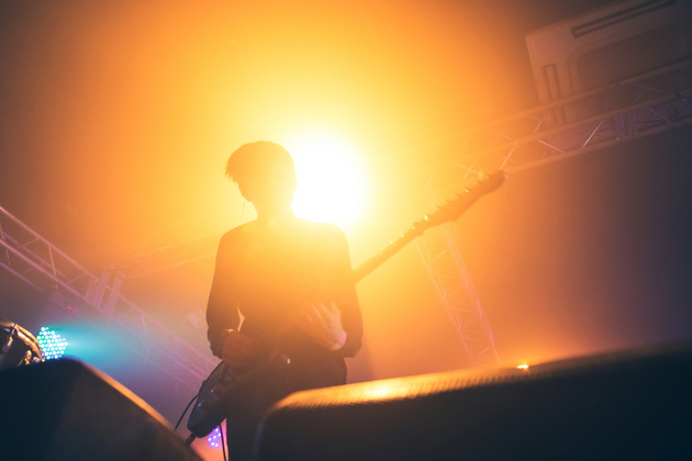 musicians with a guitar on stage lit with yellow light