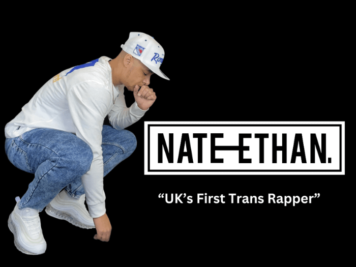 Rapper Nate Ethan wearing a white sweatshirt, blue jeans and a white baseball cap.