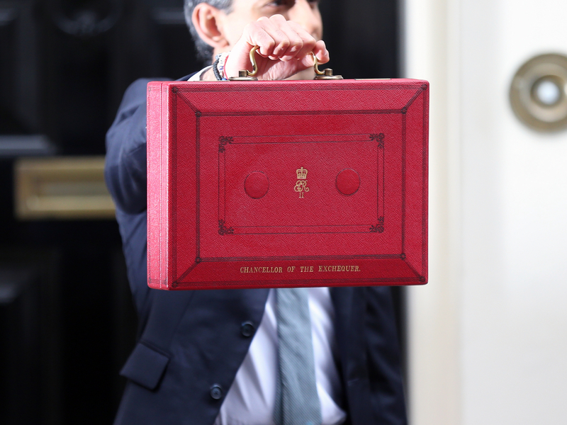 Rishi Sunak, Chancellor of the Exchequer holds up his red suitcase outside 10 Downing Street
