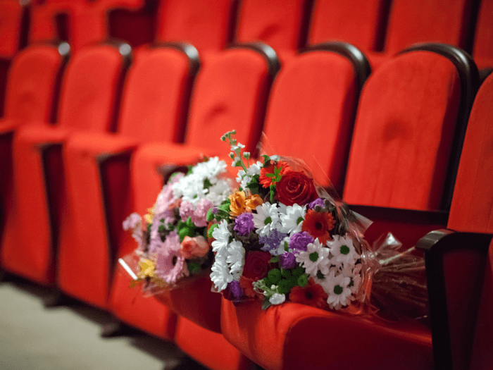 A bouquet of flowers resting on an empty theatre seat.