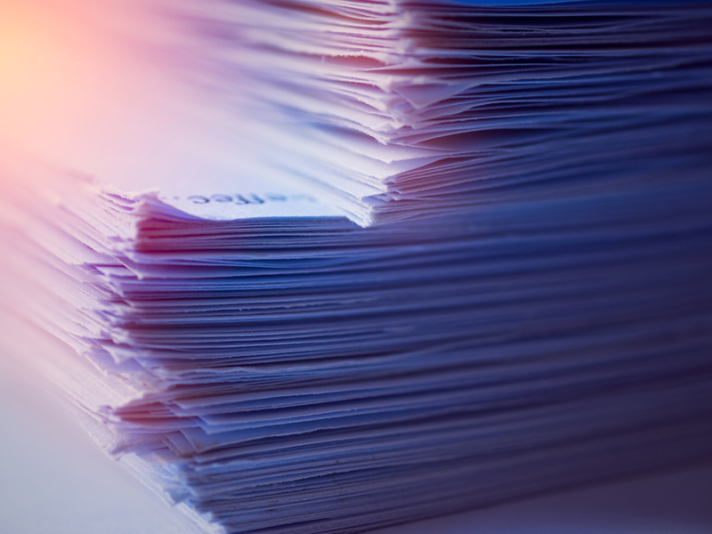 Photograph of a stack of papers with blue and purple lighting