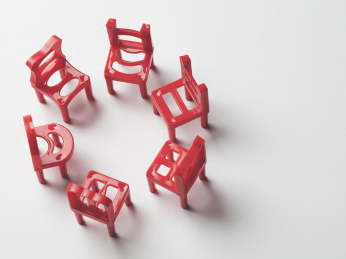 Red plastic chairs in a circle on a white and grey background