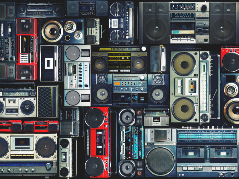 Photograph of stacks of vintage boomboxes, set up in a wall