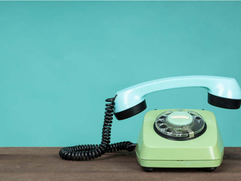 Vintage green and blue telephone against a blue background