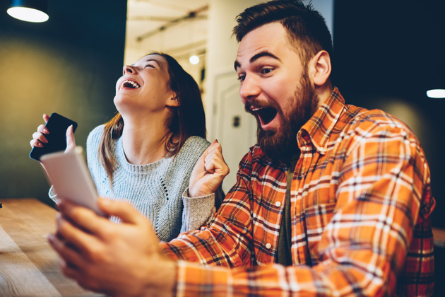 A woman and a man excited and happy holding a phone