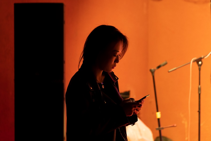 Photograph of a woman backstage, she has a concerned expression and is looking into her mob