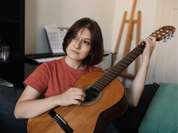 A young female musician playing acoustic guitar.